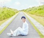 Dibalut Setelan Berwarna Putih, V Tampak Ganteng Duduk di Tengah Jalan